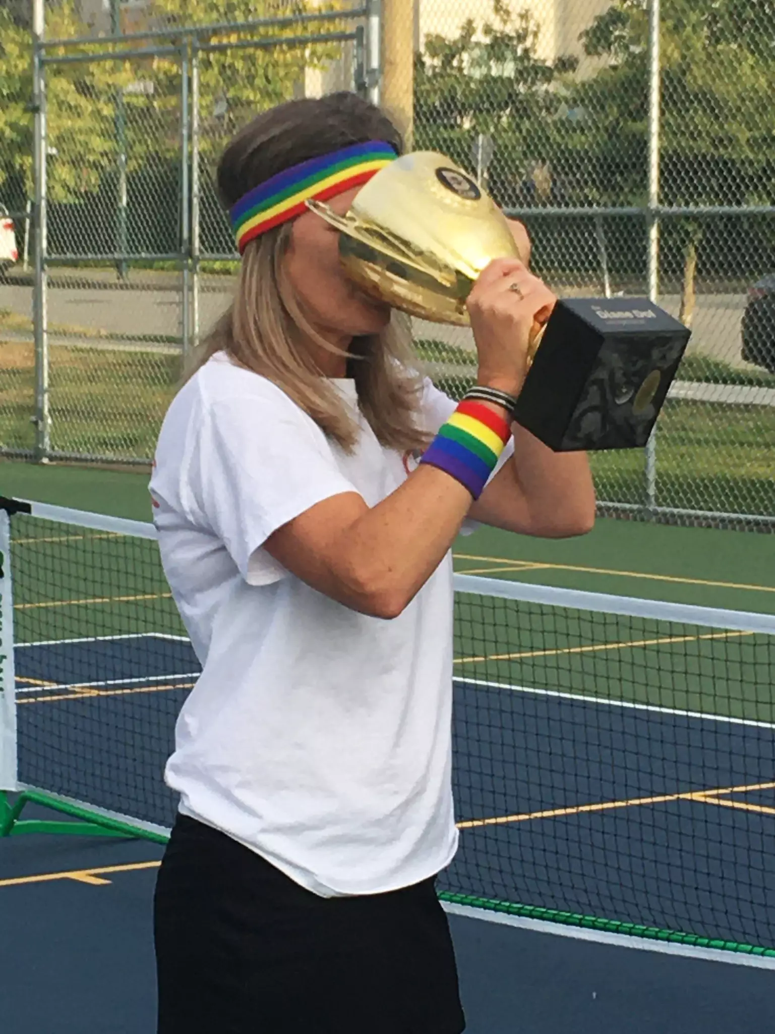 Coach Diane Dol enjoying sweet victory on the pickleball court -- drinking from the trophy!